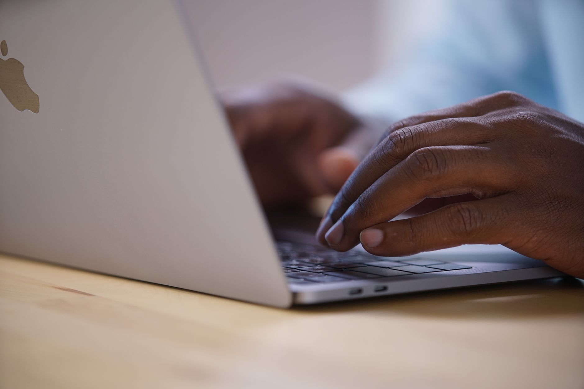 Close-up of hands carefully aligning a thin transparent panel over a laptop display in a bright room