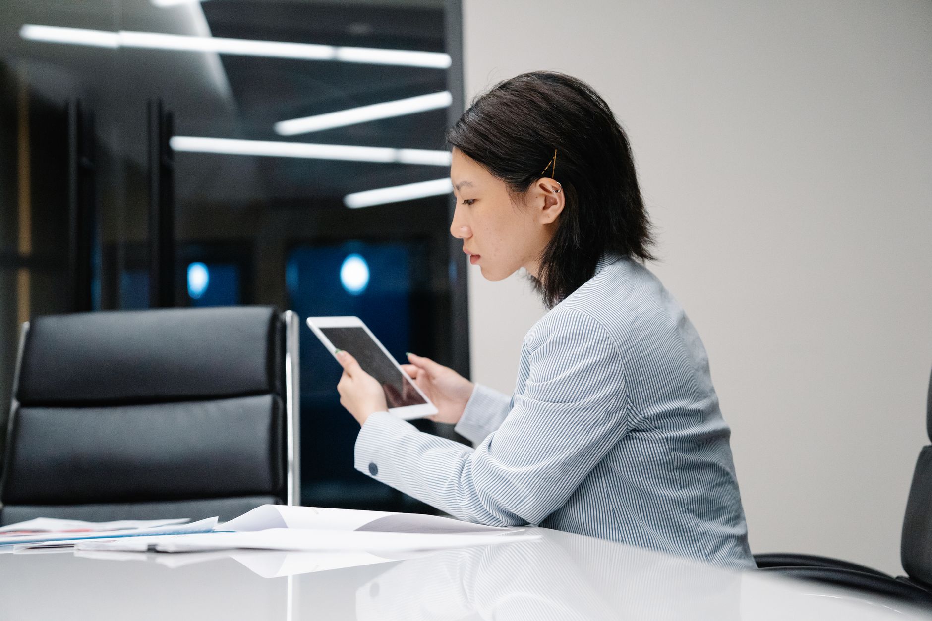 Person sitting at a tidy desk looking at a tablet while a laptop with a dark privacy screen sits nearby