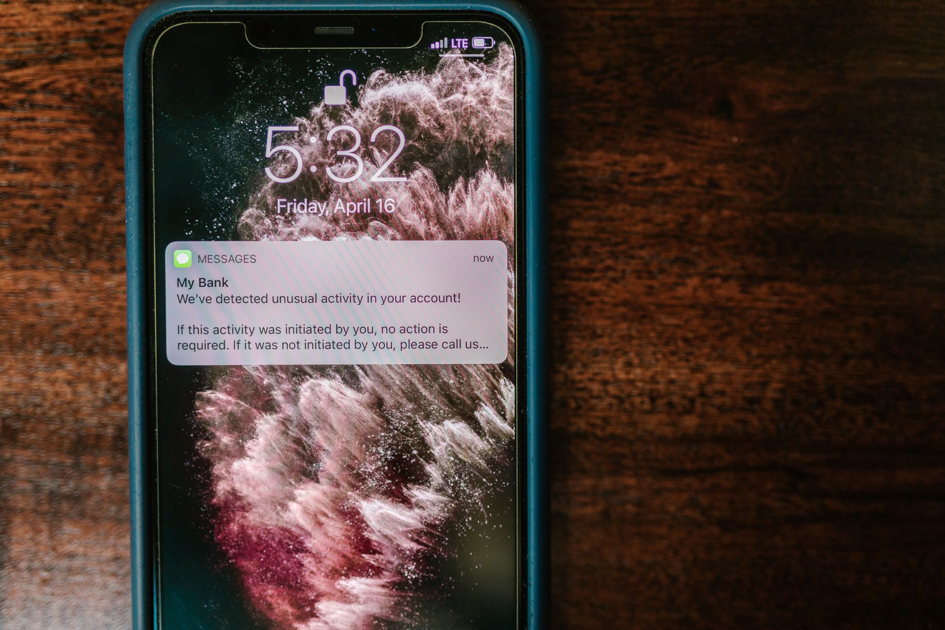 Person holding a smartphone showing a red scam alert with a lock icon in a dimly lit room.